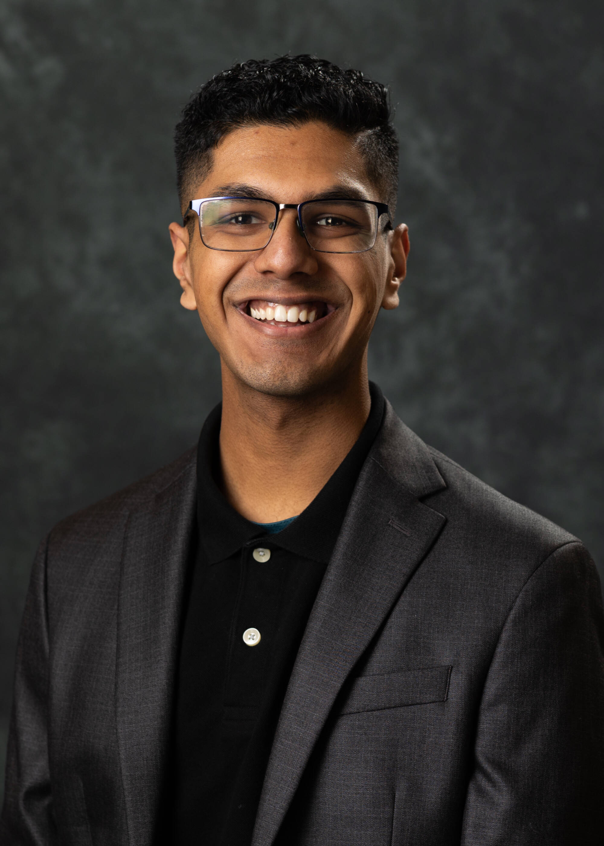 Joshua Eapen smiling in a black suit